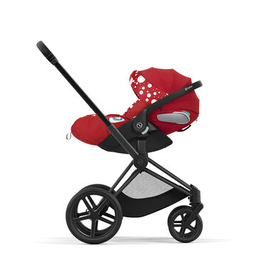Red pram with white polka dots, side view.