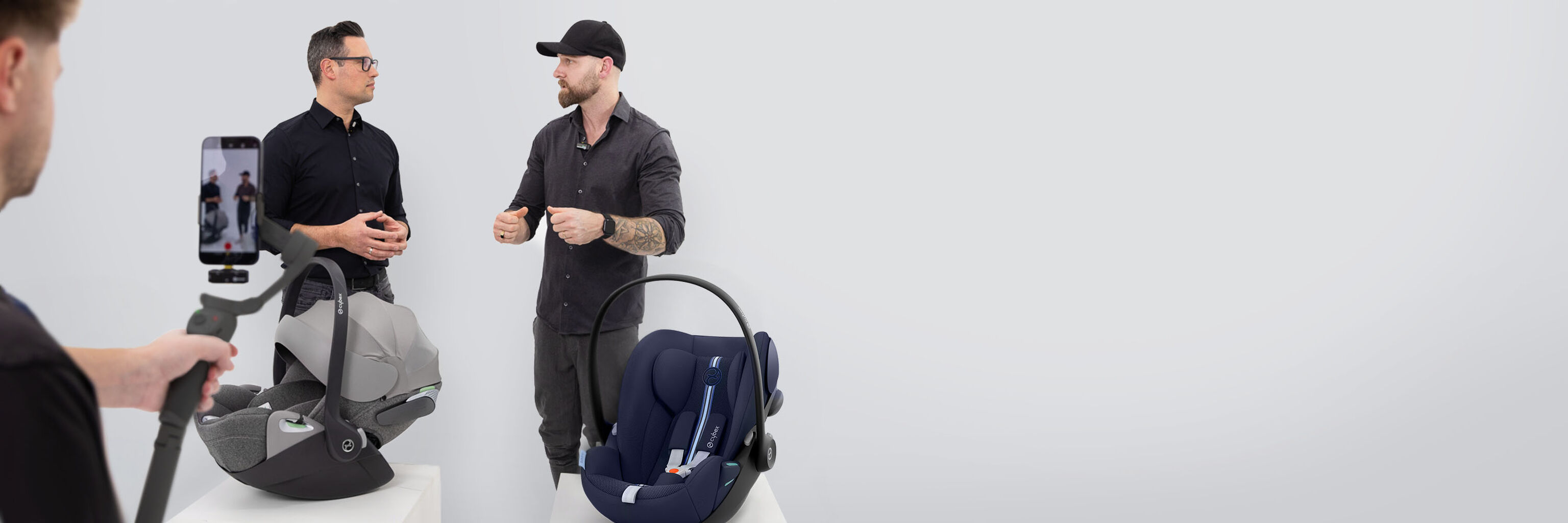 Muž nat&aacute;č&iacute; dva muže, kteř&iacute; diskutuj&iacute; o autosedačk&aacute;ch CYBEX Live.