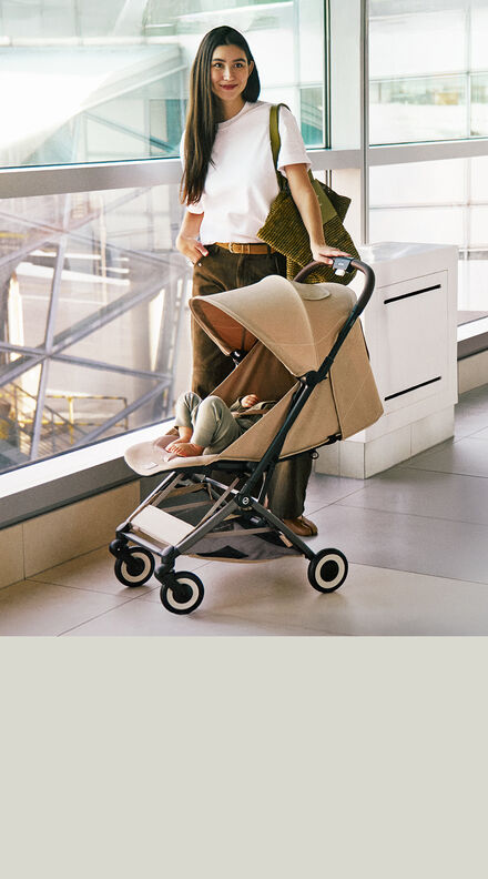 A mother with her child sitting in an Orfeo buggy at the airport.