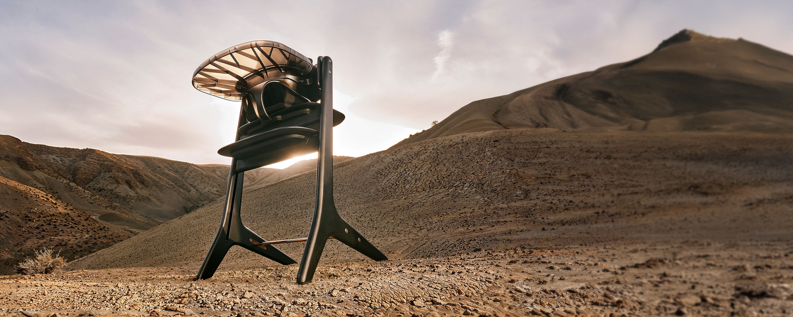 High chair placed in a dry, rocky landscape with gentle hills in the background, sunlight shining through the chair's structure.