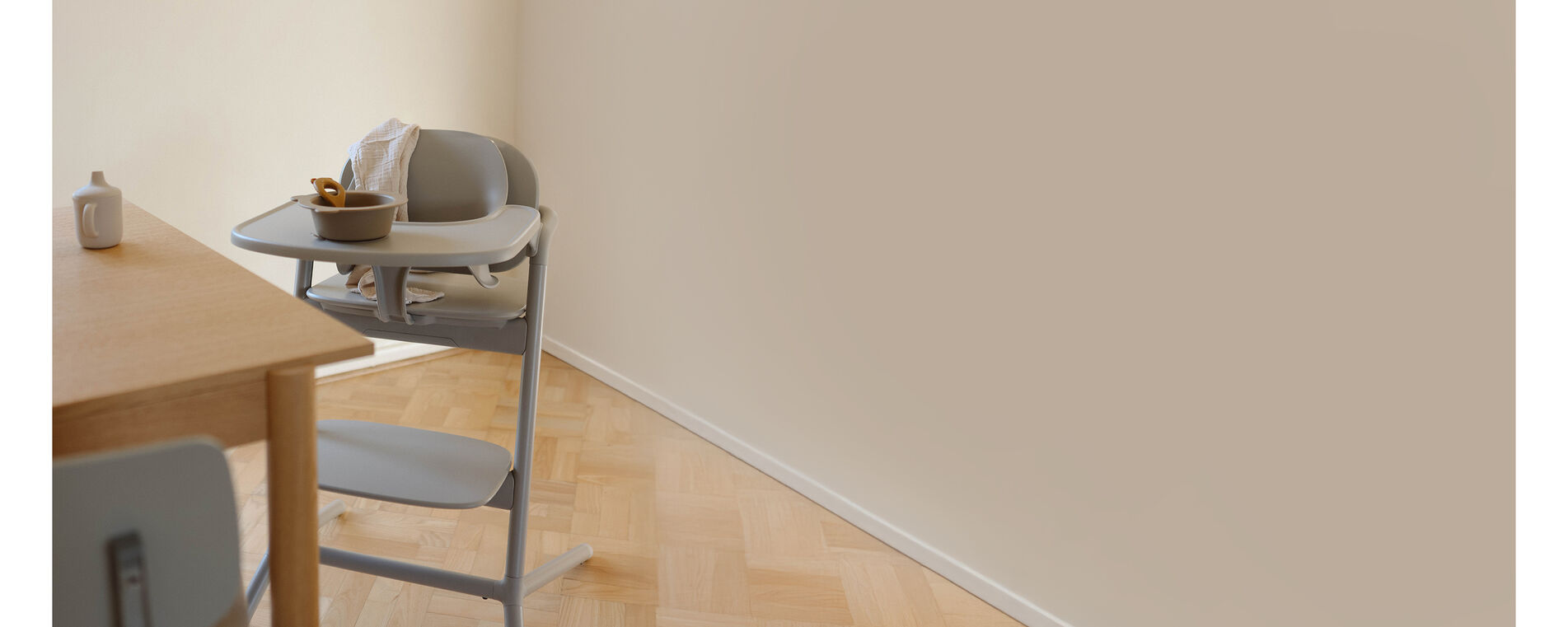 A Lemo 3-in-1 chair standing next to a table, a sippy cup on the table in front of it. 