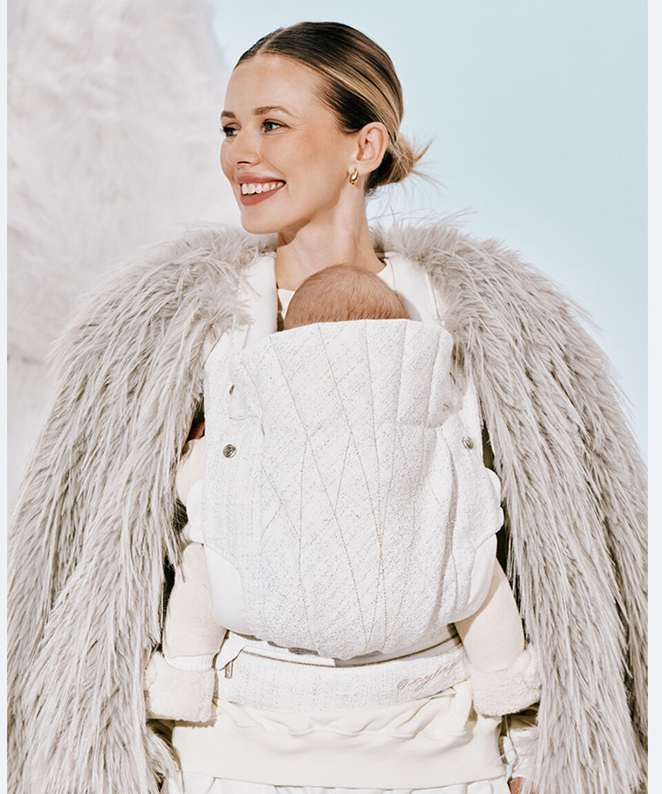 Une femme sourit en regardant vers la gauche tandis qu’elle tient son bébé dans le porte-bébé CYBEX.