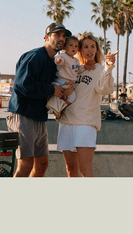 A mother points at something, holding her child. Next to them is their father. All three look in the same direction. On the image, it reads "New".
