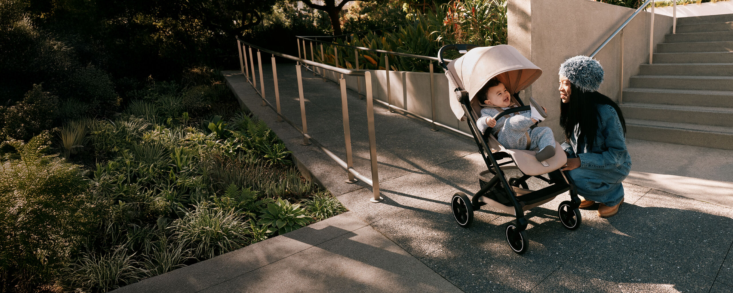 A mother kneeling next to her Beezy buggy where her child is laughing inside.