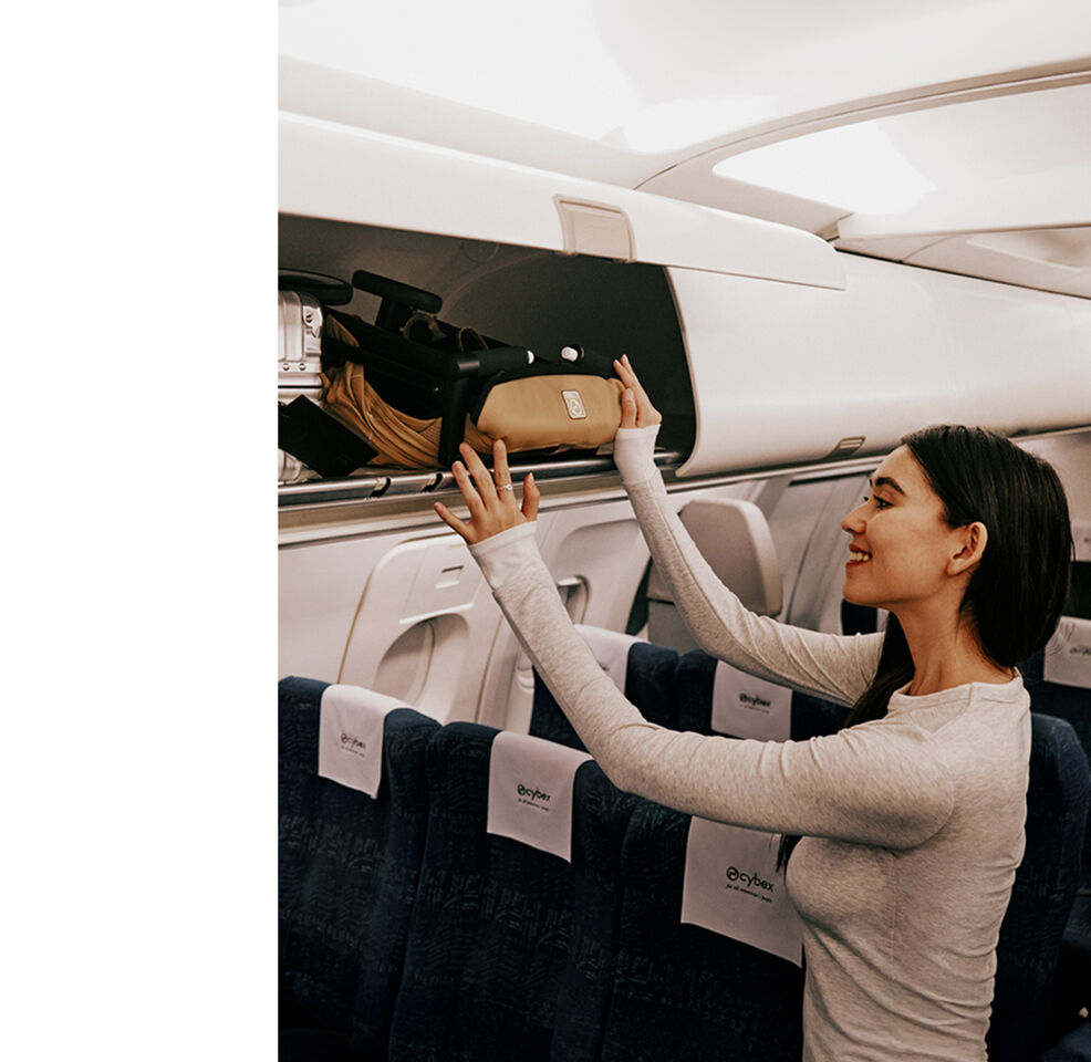 A woman storing a folded Libelle in an overhead compartment of an airplane.