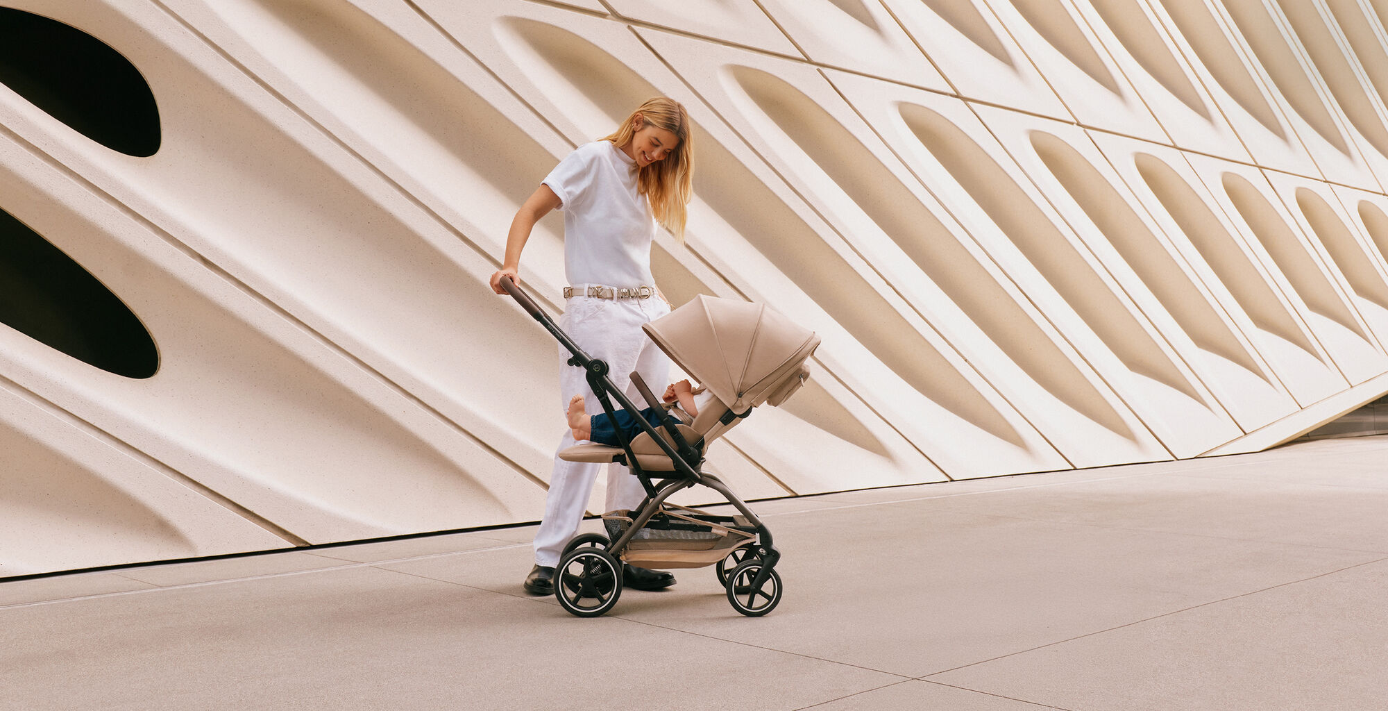 A blonde mother looking down at her toddler in an Eezy S Twist +2 buggy with the sun canopy down.