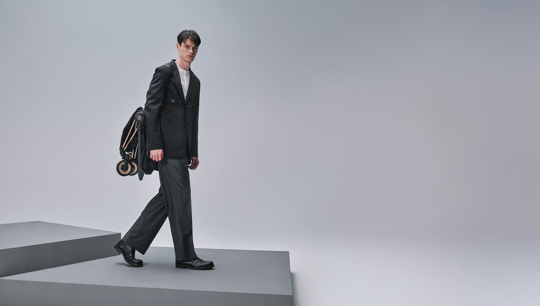 A man carrying a folded Co&yuml;a Style buggy while looking directly into the camera.