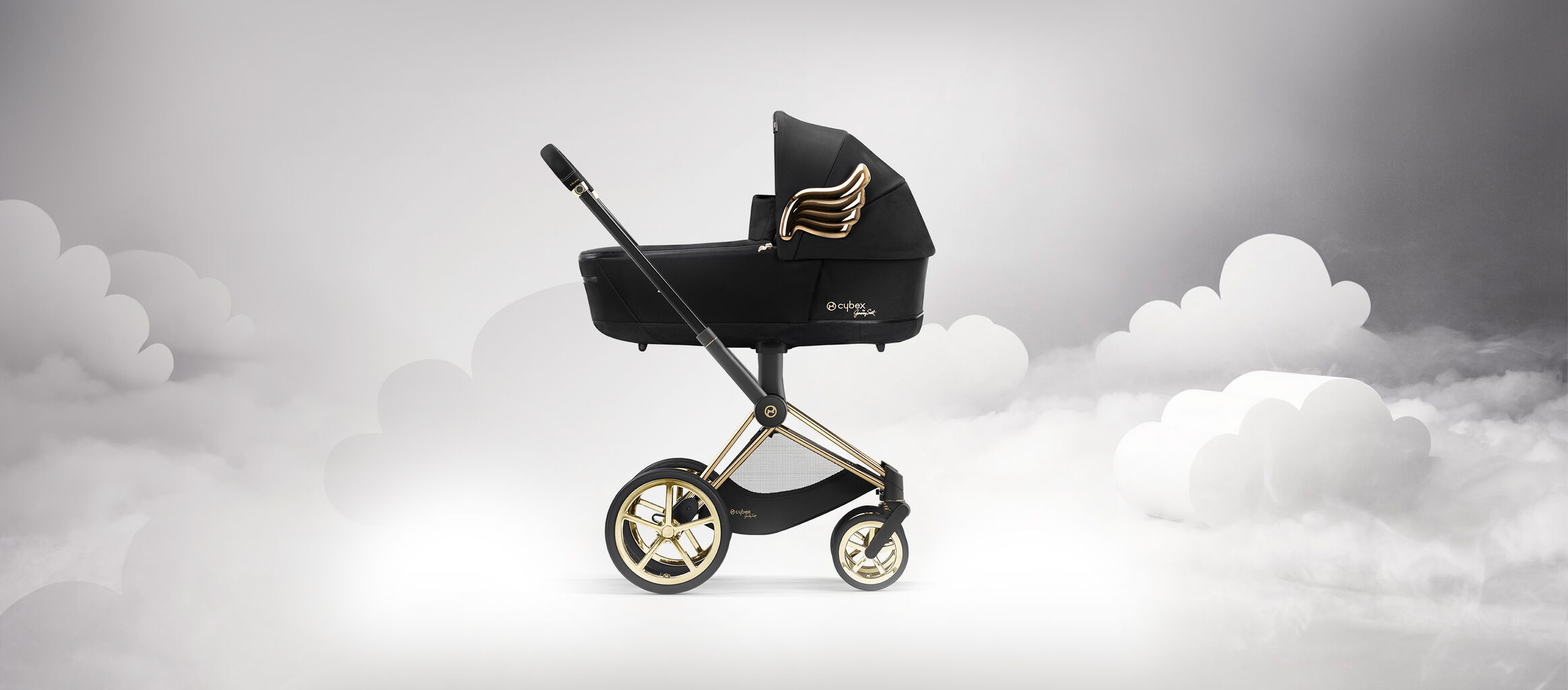 Black pram by Jeremy Scott Wings featuring golden wings, against a backdrop of clouds.
