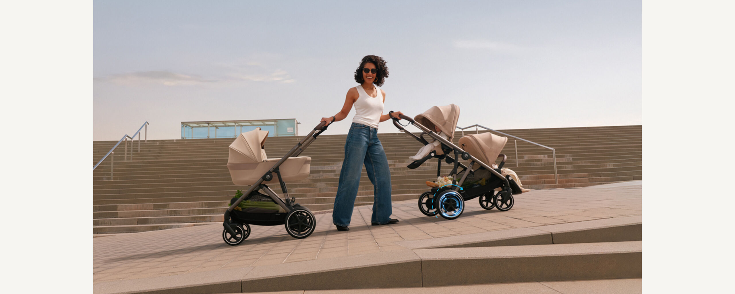 A mother laughing into the camera, holding two e-Gazelle S' with each hand as she's standing on an incline, showcasing the e-power the e-Gazelle S has.