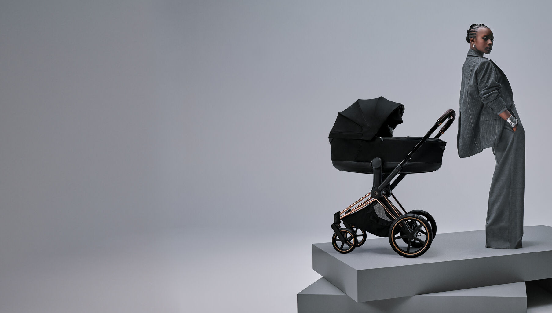 A woman standing next to the Priam Style, both on two gray platforms.