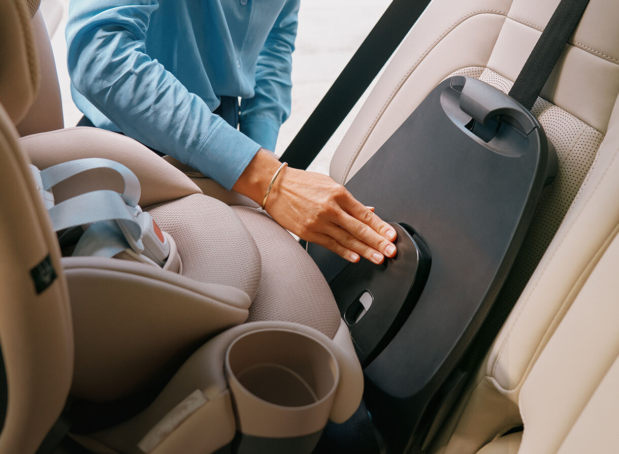 A mother installing a base with a car seat on it in the back of her car.