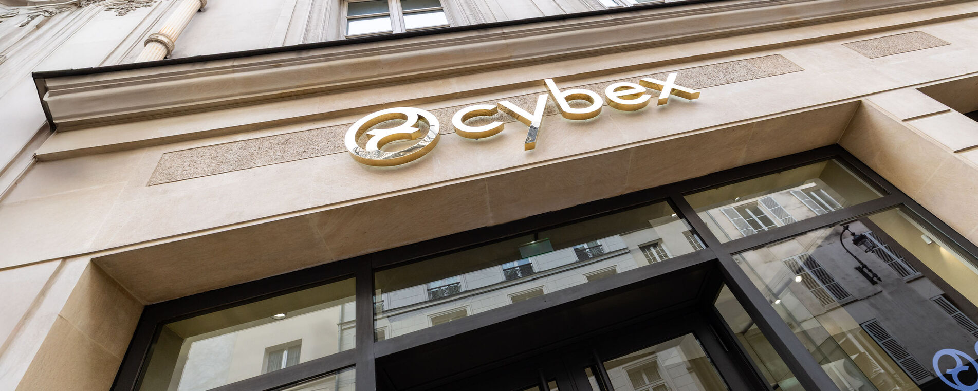 Shining golden CYBEX logo on the modern store façade, captured from a low-angle perspective for a striking, elegant effect.