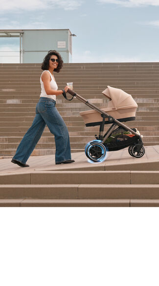 A woman pushing an e-Gazelle S e-stroller up a hill.