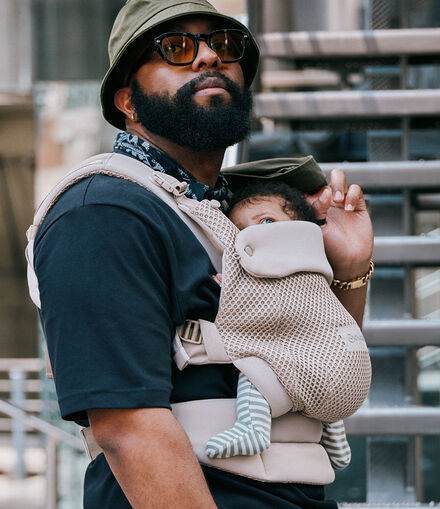 A man and his baby that is in an Amya baby carrier looking up into the sky, in the same direction.