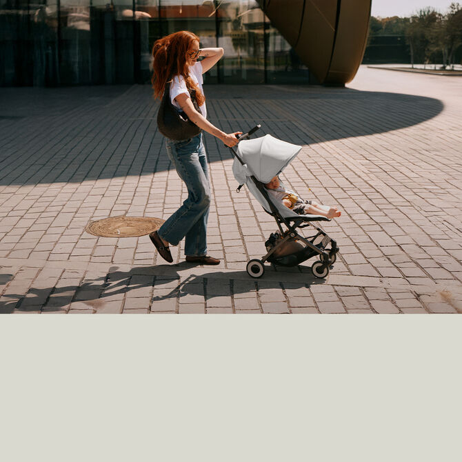 A woman pushing her toddler in a Libelle lightweight stroller.