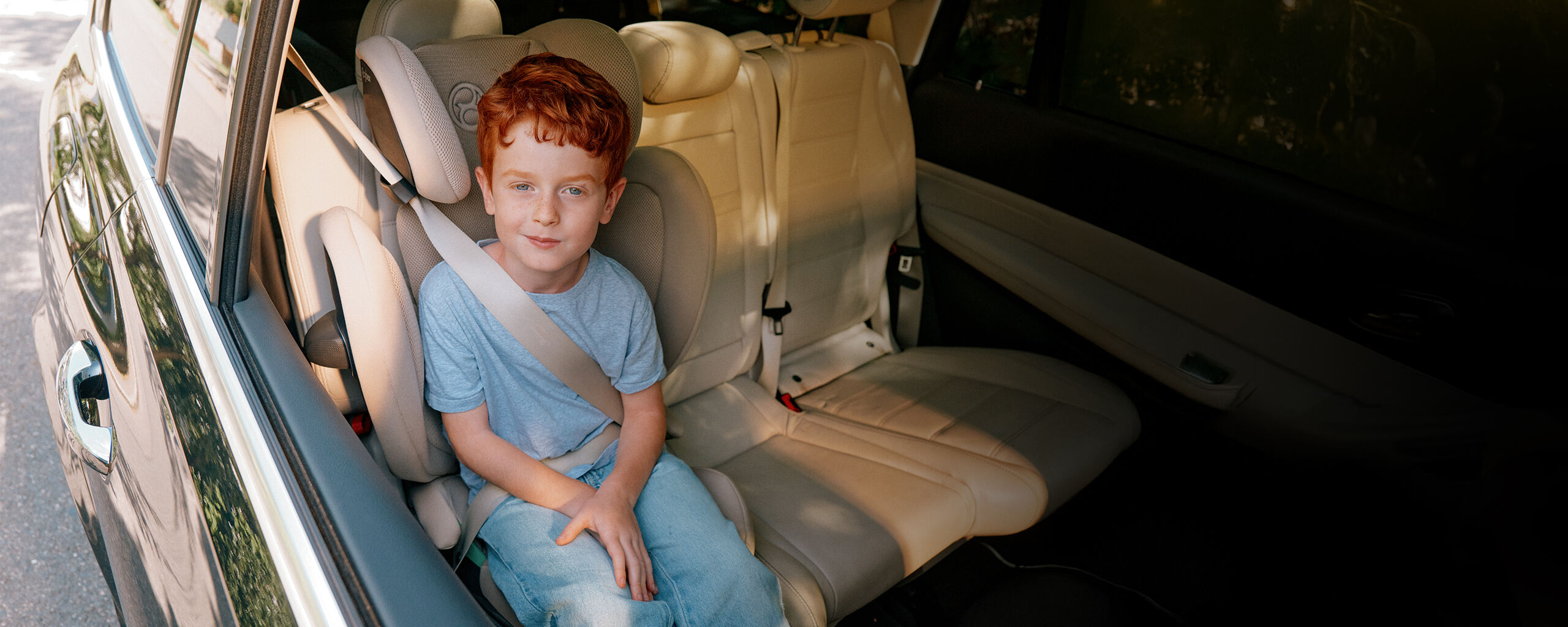 A boy is safely seated in the Solution G2 travel car seat in the back of a car.
