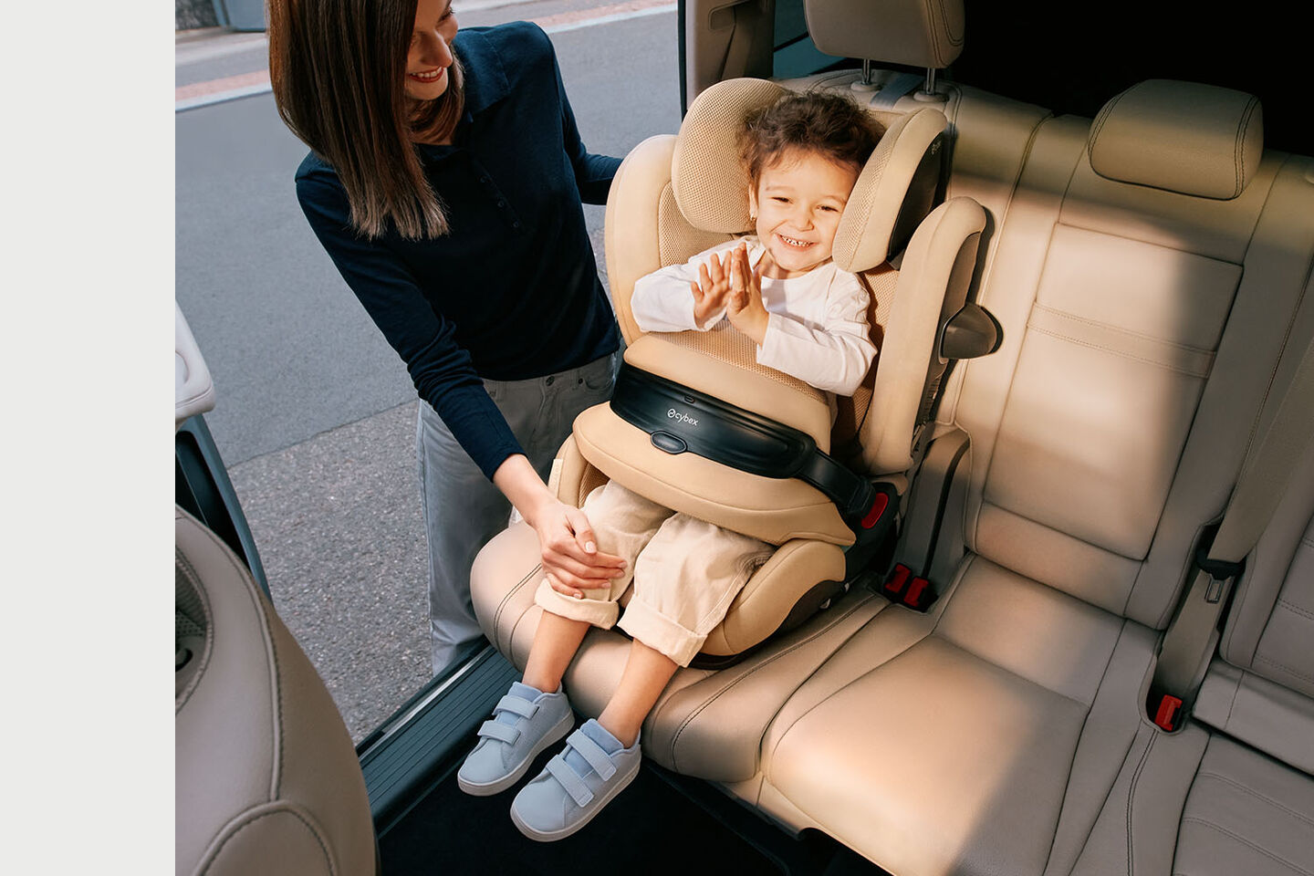 Pallas G3 growing child seat, a smiling child sits in the car seat while an adult holds their hand