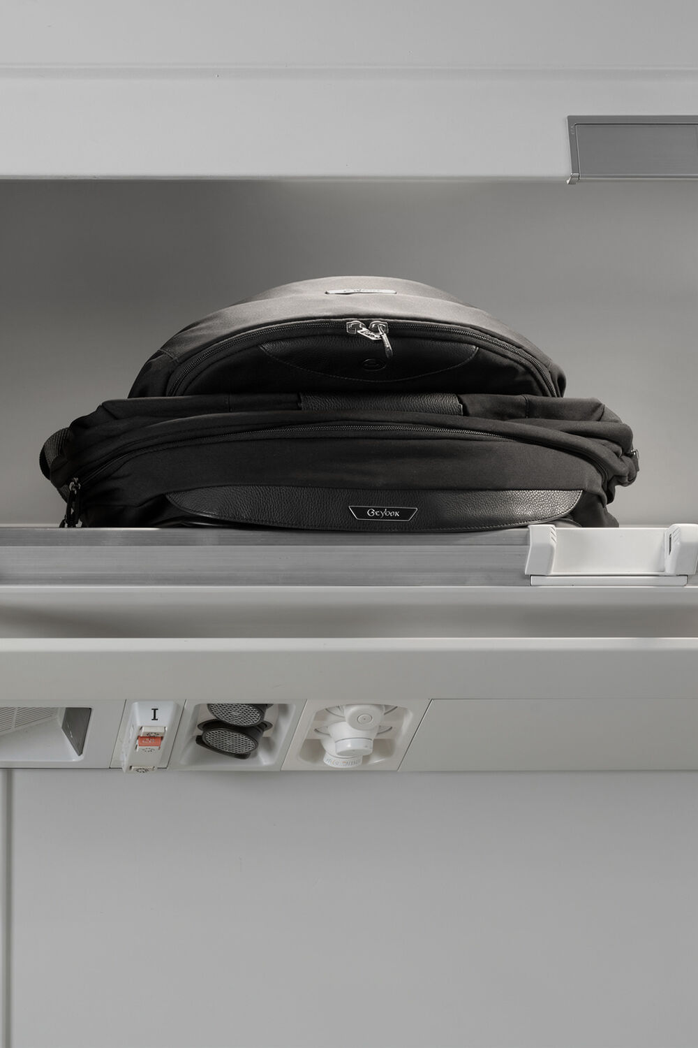 A folded up Fold Lux Carry Cot in an overhead compartment of a plane.