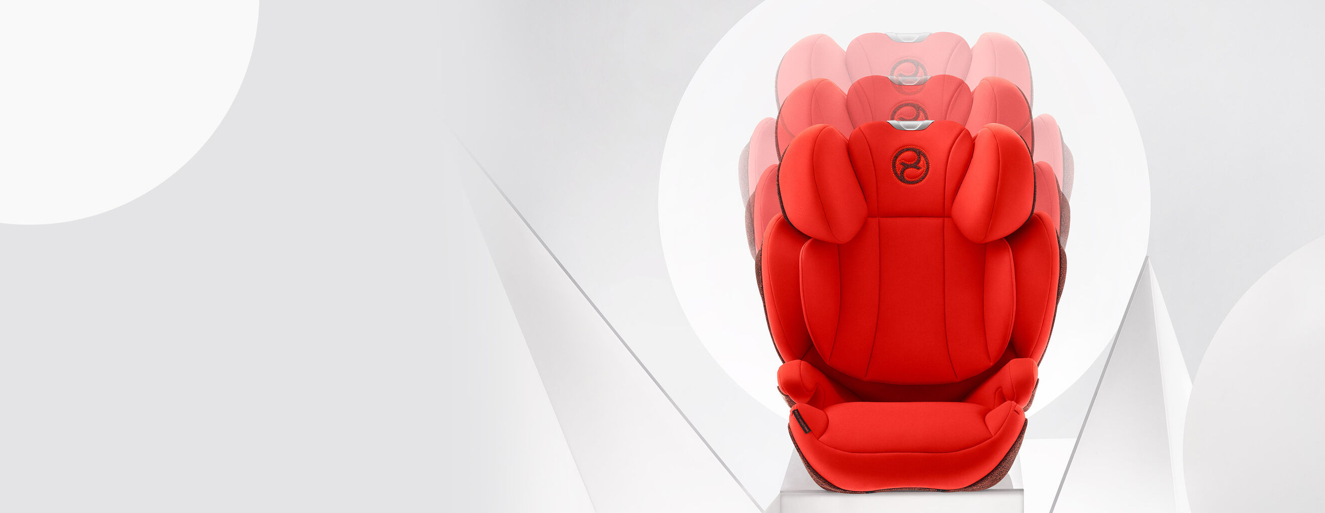 A red child car seat with an adjustable headrest against a grey background.