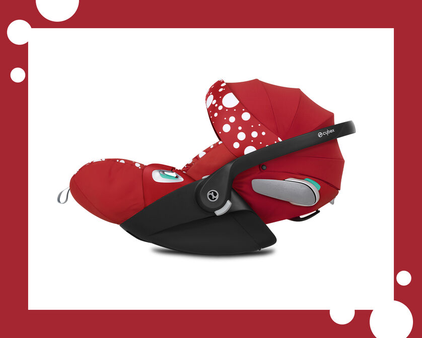 A red Cybex car seat with white polka dots and a black frame, shown from the side.