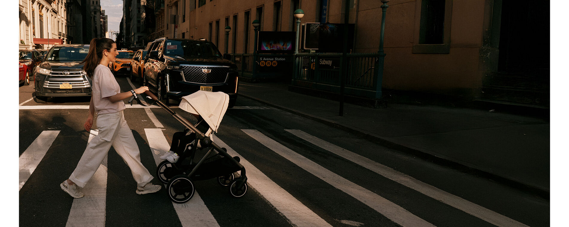 A woman pushing her e-Gazelle across a street, cars behind her waiting patiently for her to cross.