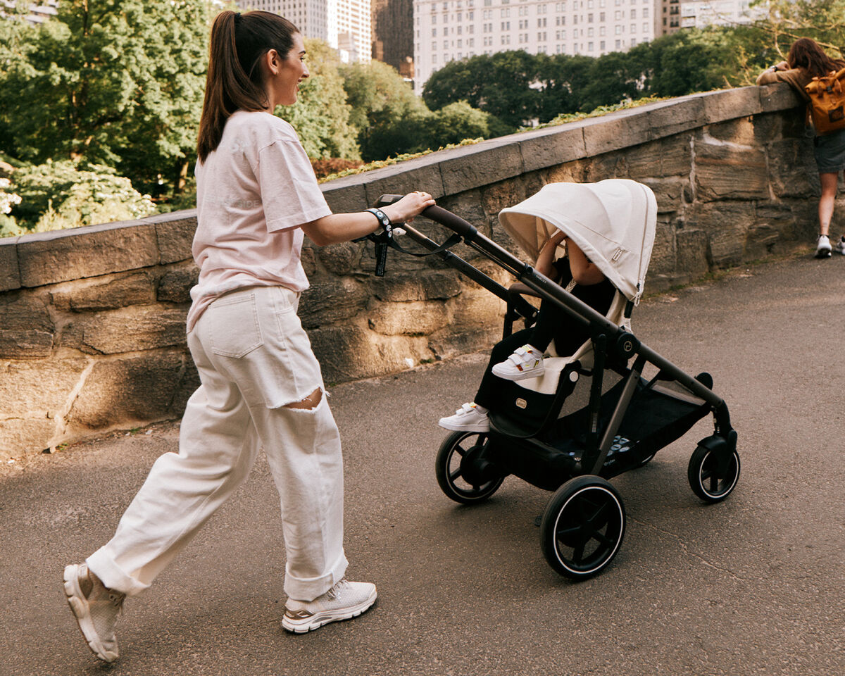 A woman pushing a pram along a park path.