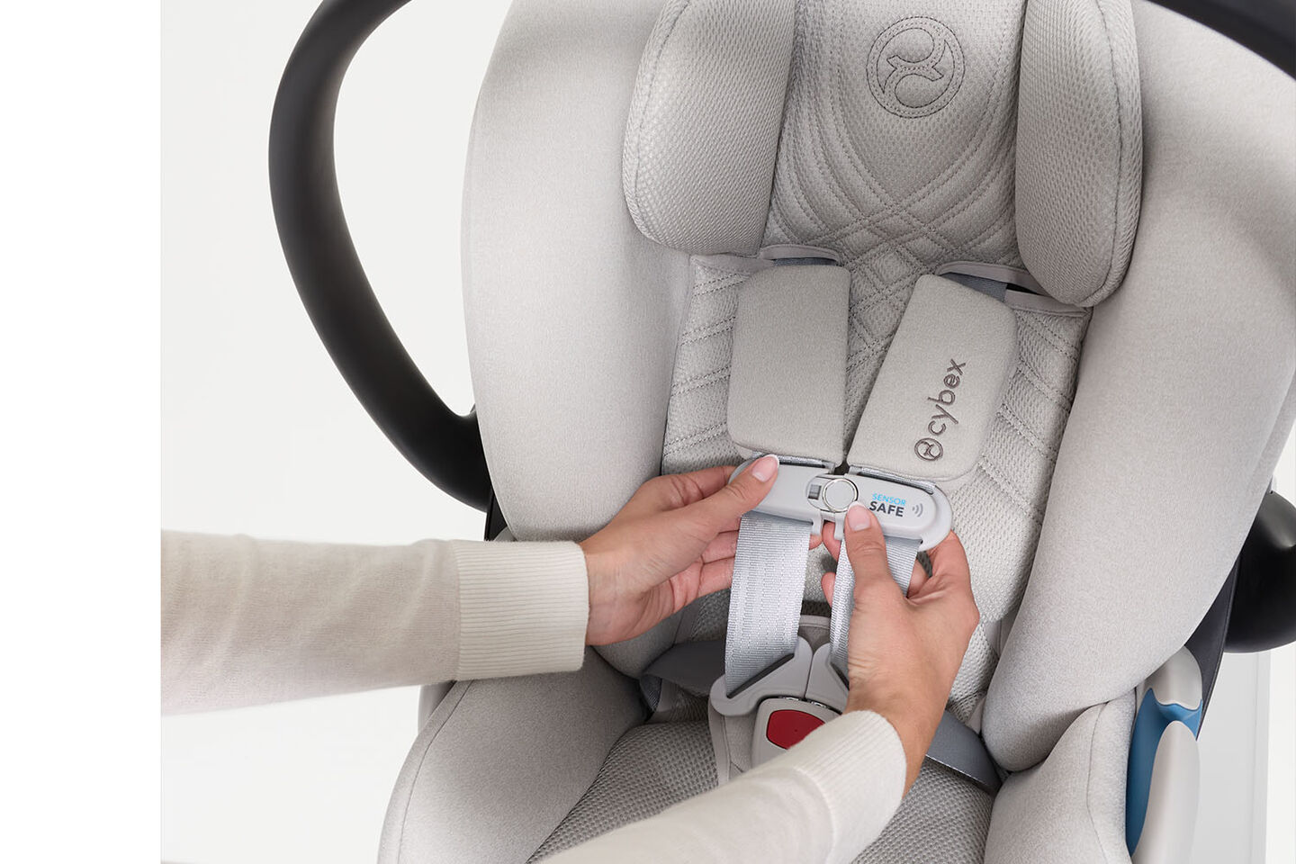 A woman clicking the SensorSafe clip together of a CYBEX car seat.