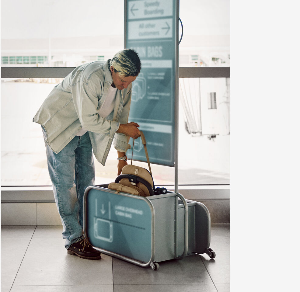 Man placing folded compact stroller Orfeo into airport cabin baggage sizer