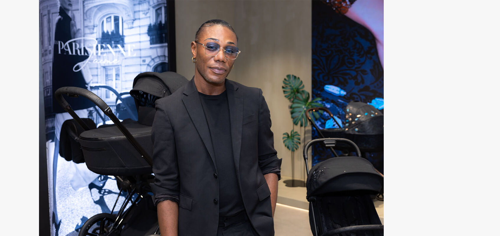 CYBEX store interior: man dressed in all black with stylish tinted bluish glasses stands inside the store. In the background, a La Parisienne pushchair is visible.