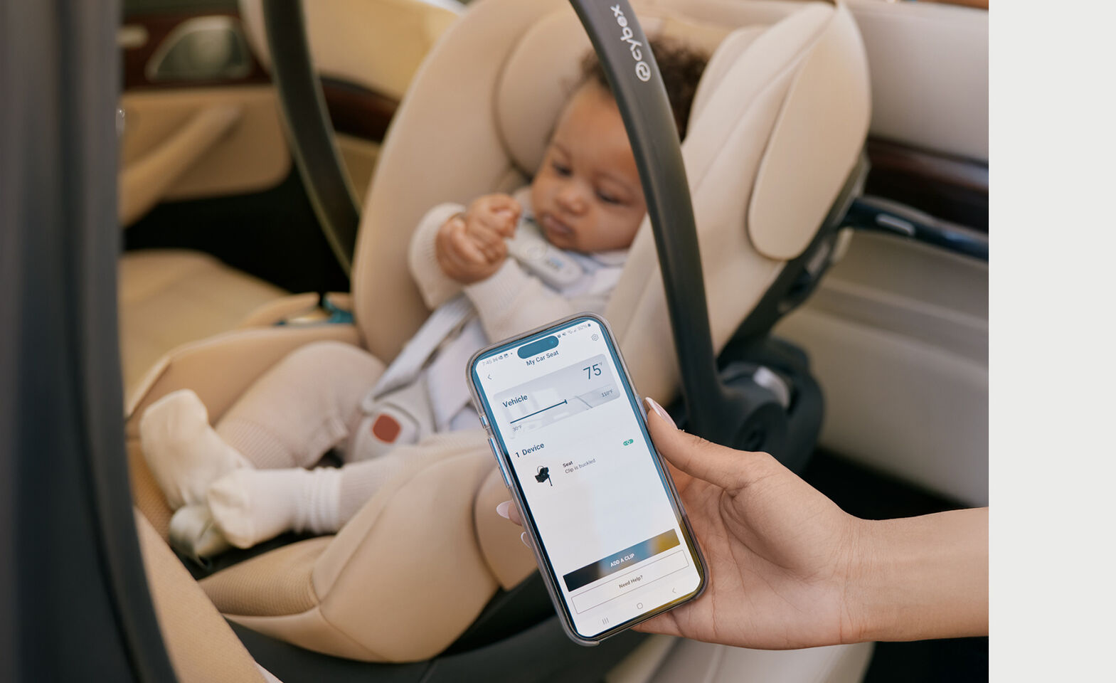 A mother holding her phone in the camera that shows the temperature inside the vehicle and that the Cloud G Pro with her child inside is still safely buckled in.