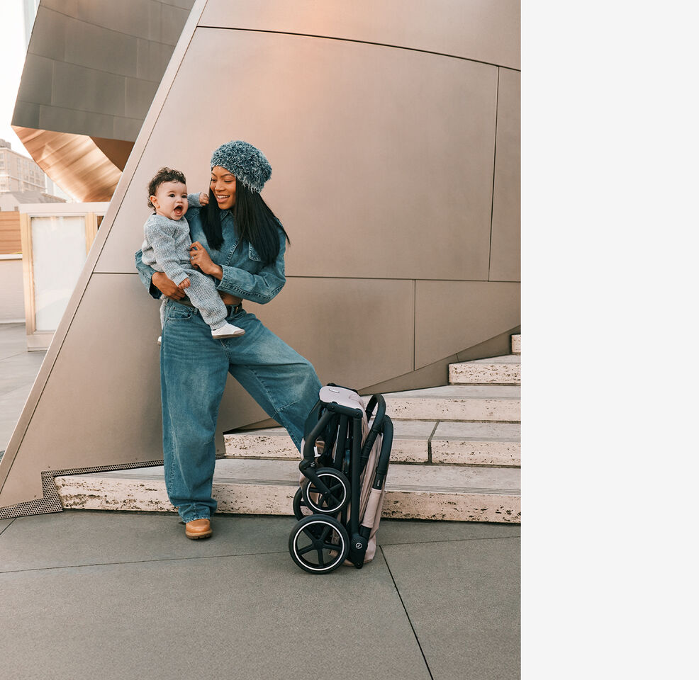 A woman tickling her baby. A folded up Beezy stands before them.
