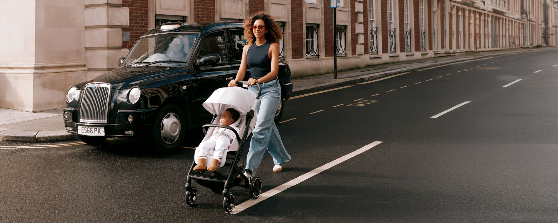 A woman pushing her CYBEX buggy across a street in the UK.