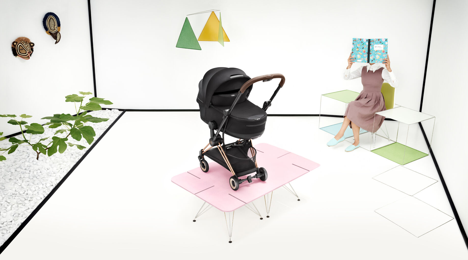 A Coya buggy with a foldable Cot attached. Behind sits a woman that hides her face behind a book.