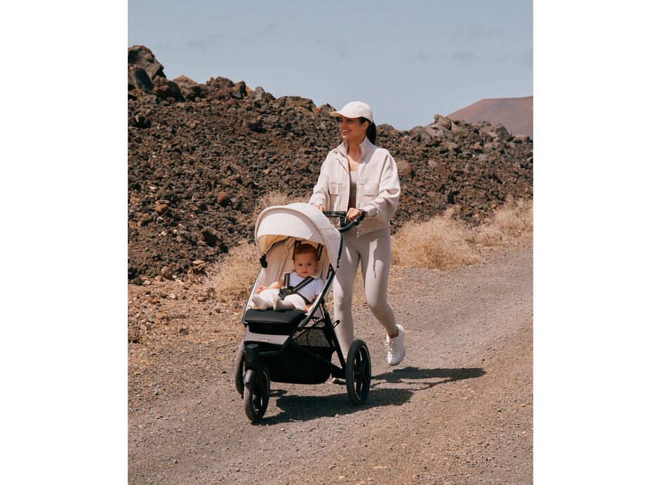 A woman pushing her Avi Spin stroller on a rocky path as she and her child are on a hike.