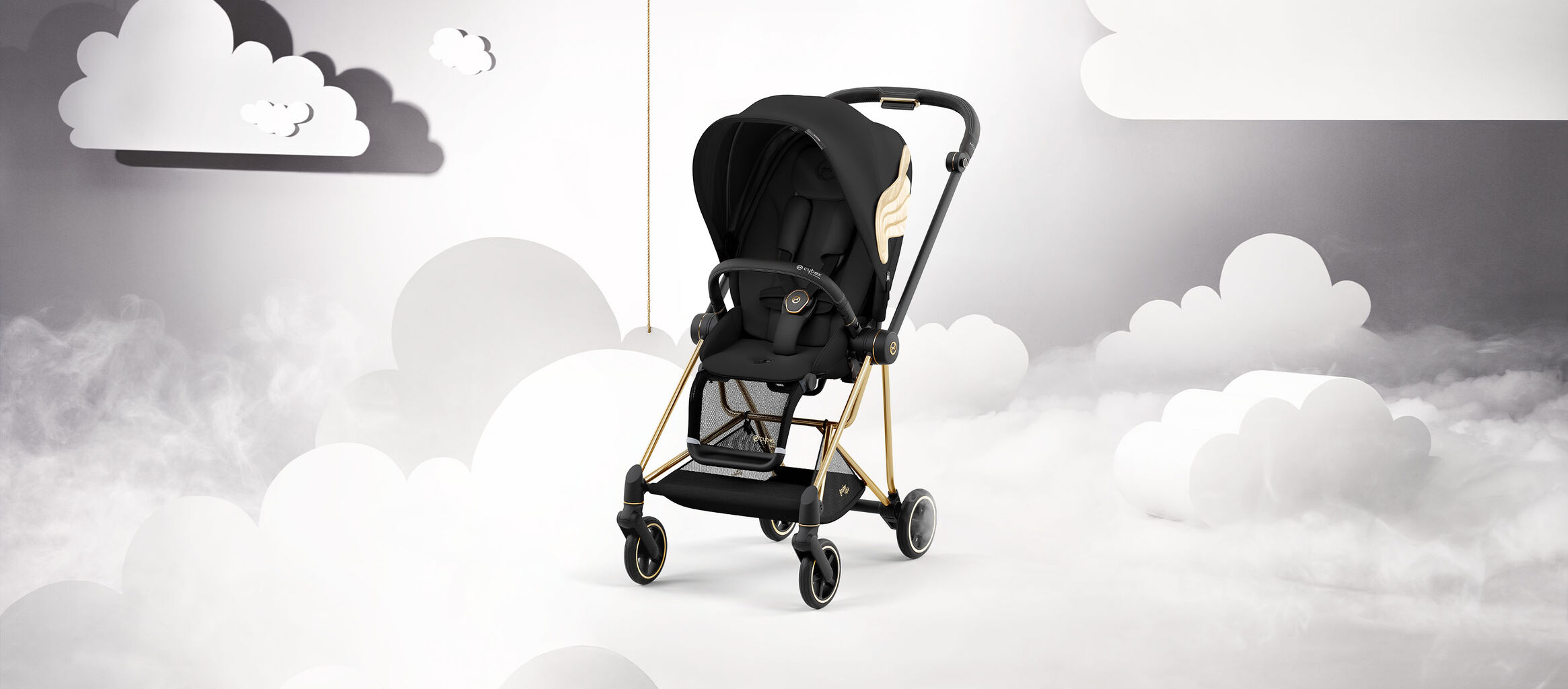 Black pram by Jeremy Scott Wings with gold accents, set against a cloud backdrop.