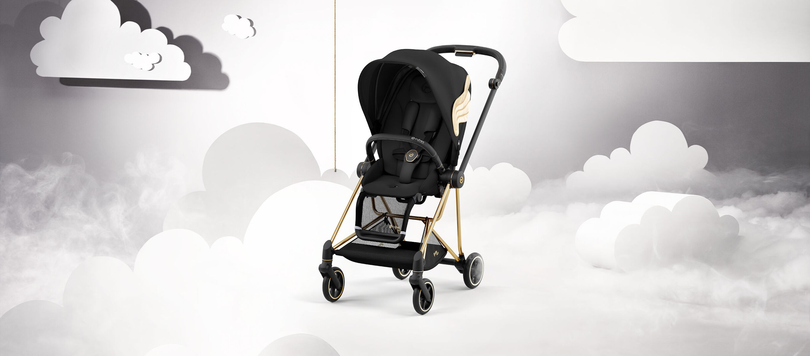 Black pram by Jeremy Scott Wings with gold accents, set against a cloud backdrop.