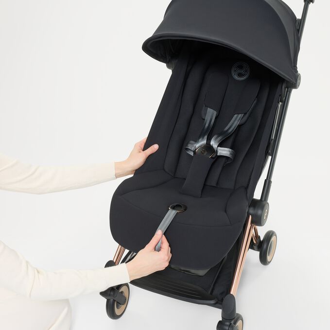 Ein Bild des CYBEX Platinum Coya mit Cot Stroller, das das Merkmal Einhand-Gurtsystem hervorhebt.